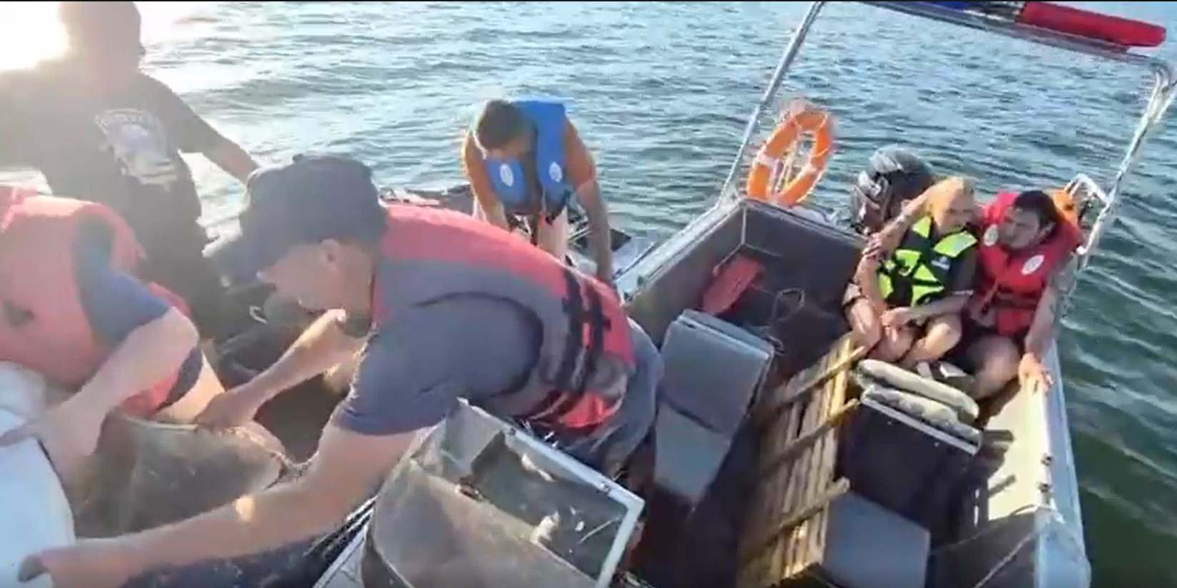 Buqtyrmada qutqarýshylar aýdarylǵan qaıyqtan adamdardy evakýasııalady